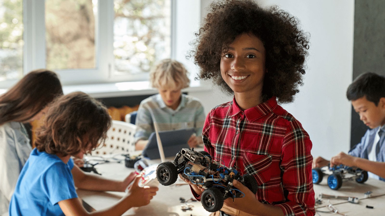A Black student holding a small robotic vehicle.