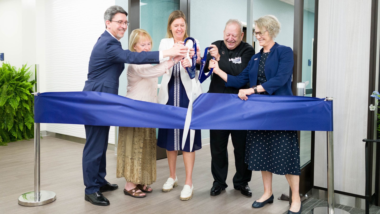People cutting a giant ribbon.