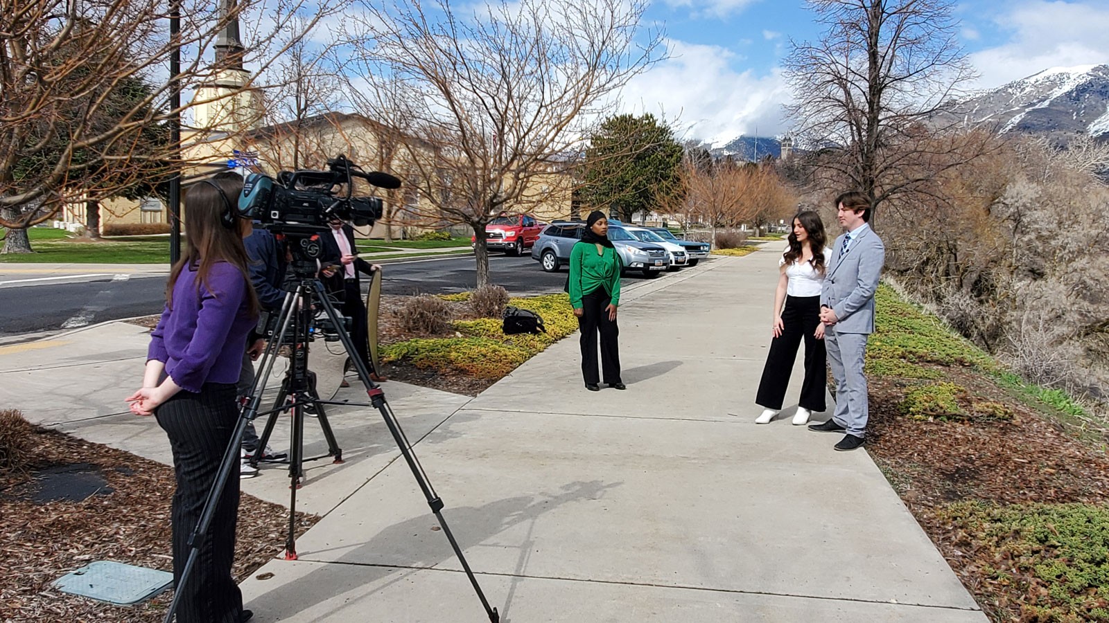 Students using a television camera to film a news segment.