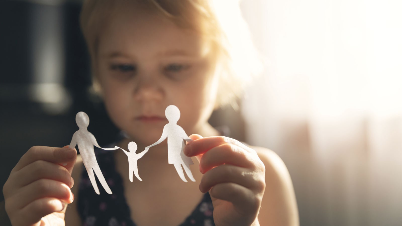 A girl playing with a paper-doll family.