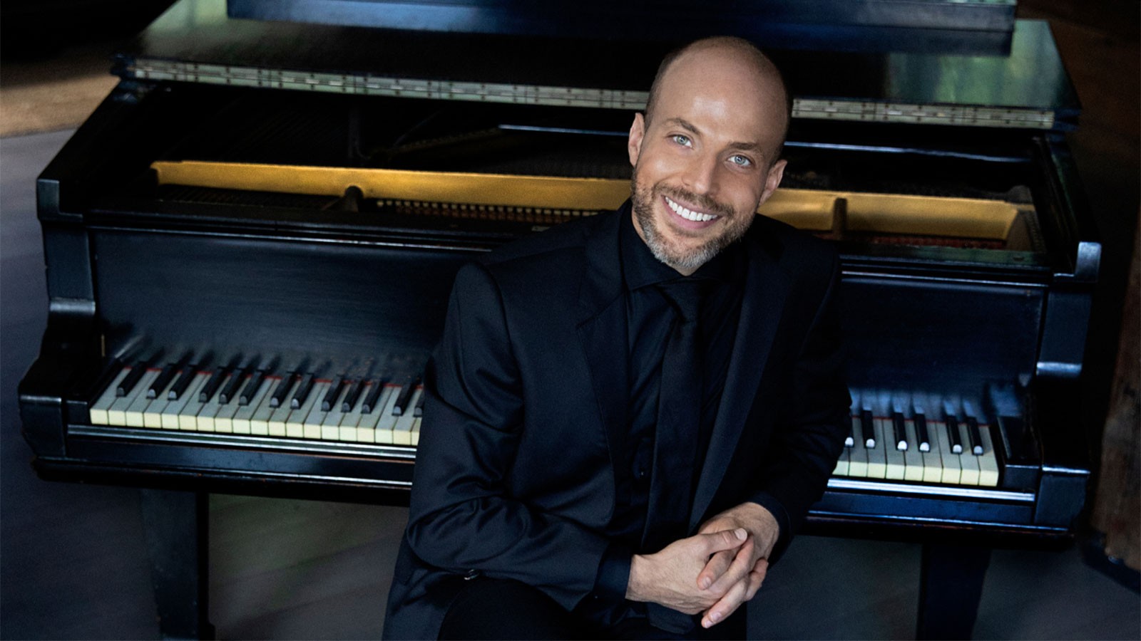 Orion Weiss posing on a piano.