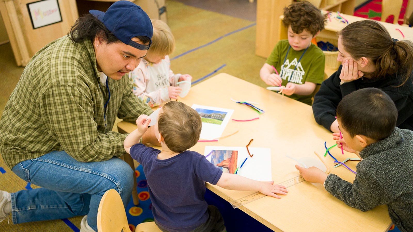 Adults talking with children in a classroom.