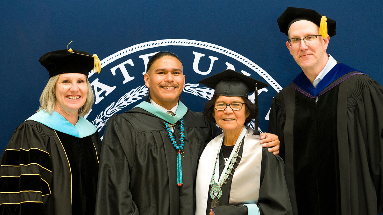 People in graduation robes posing for a photo.