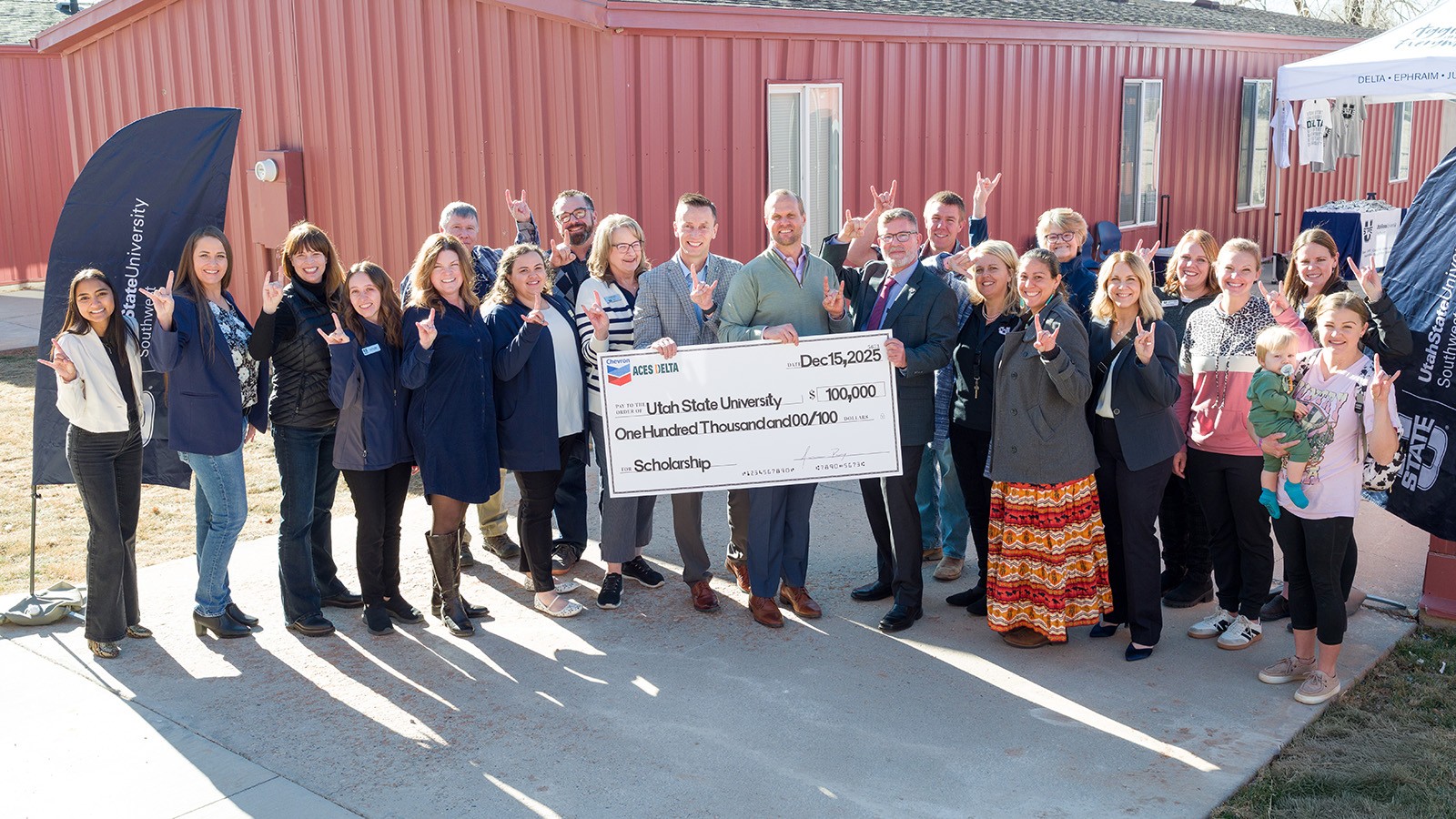 A group of people celebrate during a check presentation at the USU campus in Delta.