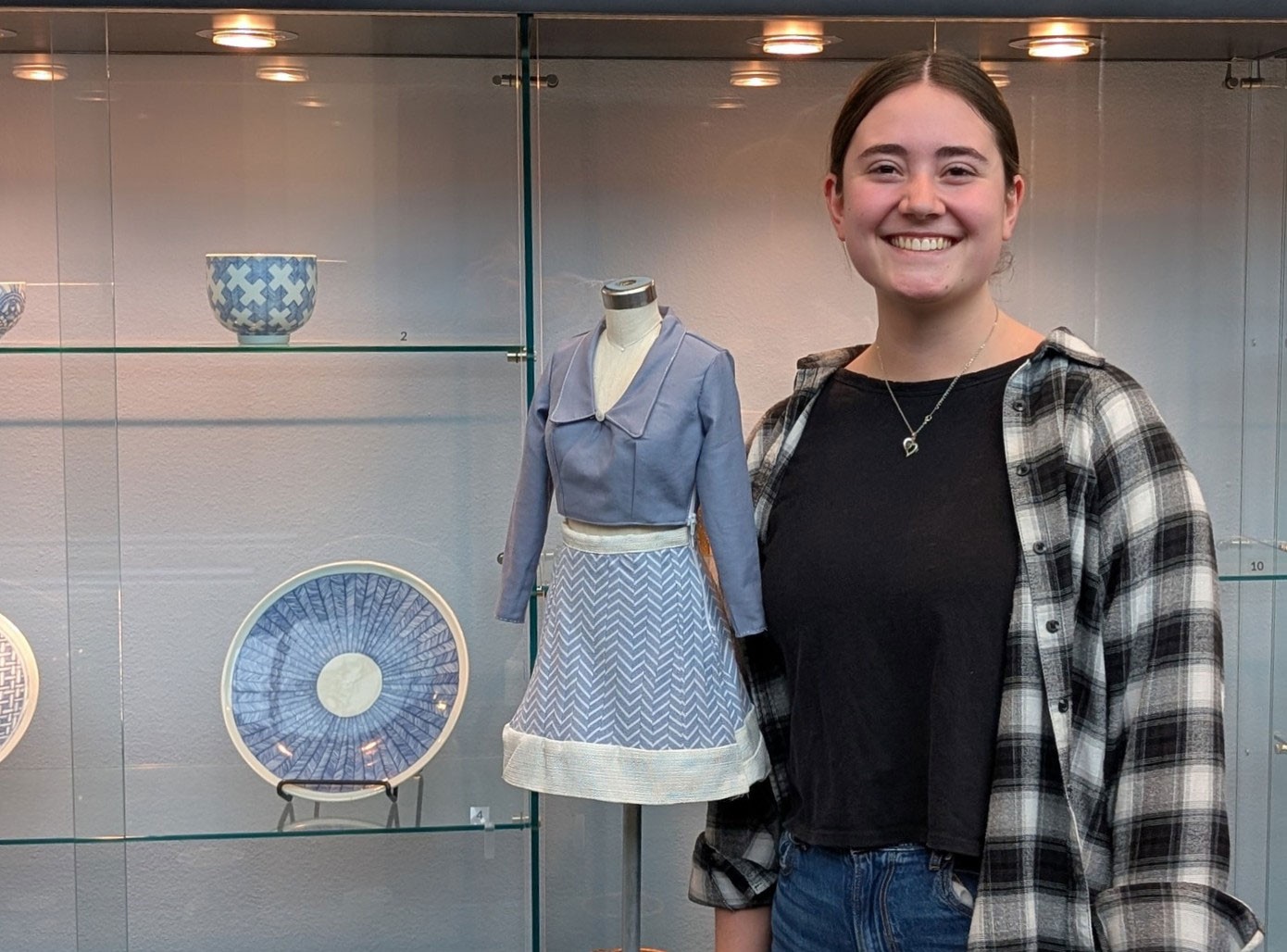 Rachel Godfrey posing next to a half-size dress and blue dishes.