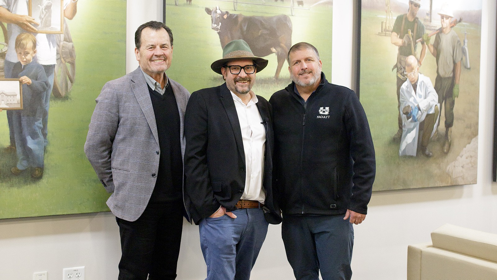 Three men take a photo in a painting portrait gallery.