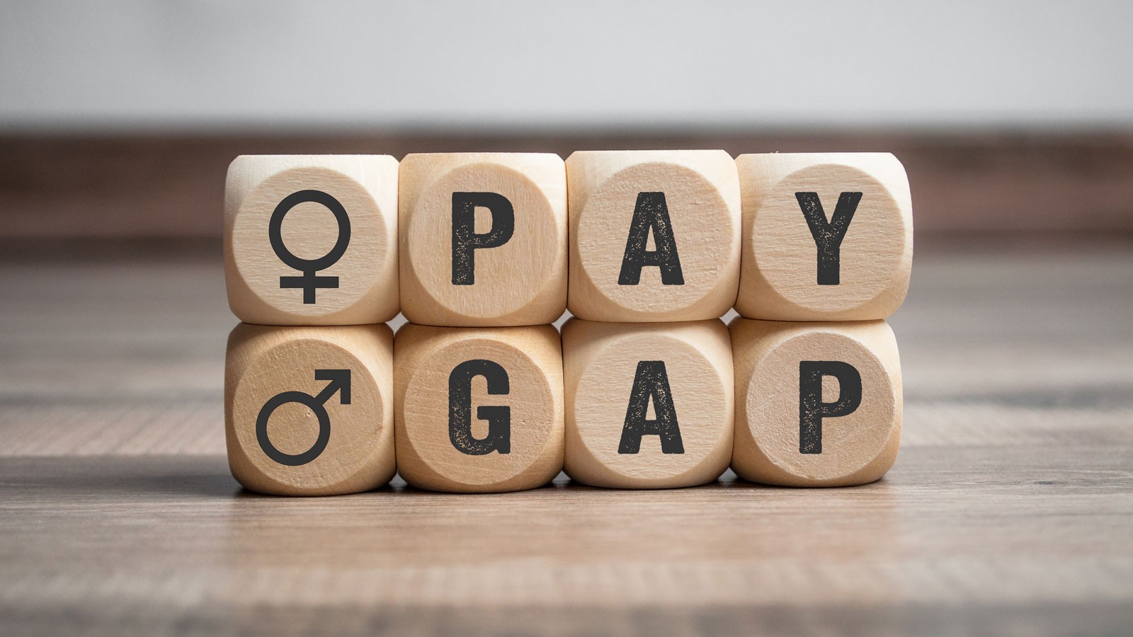An illustration of wooden blocks spelling out the words "pay gap."