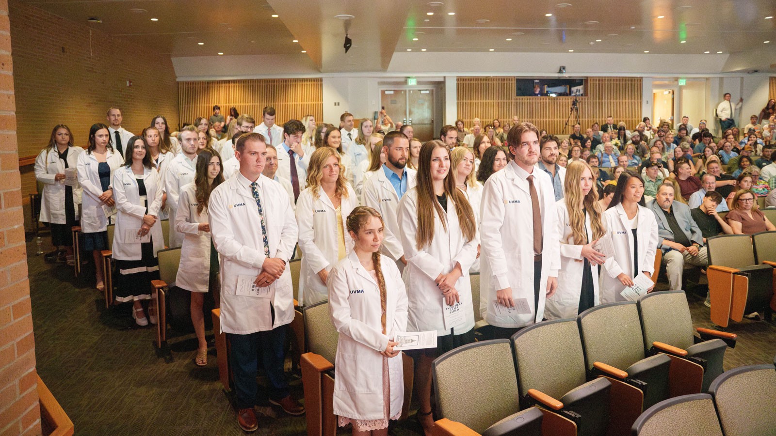 People wearing white coats standing in a conference center.