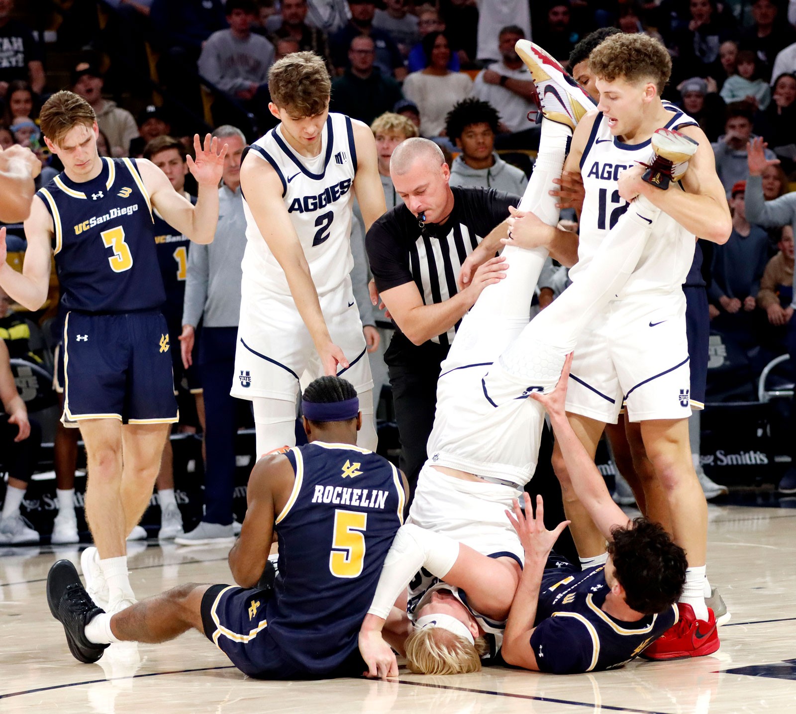Karson Templin upside down in a pile of players on a basketball court.