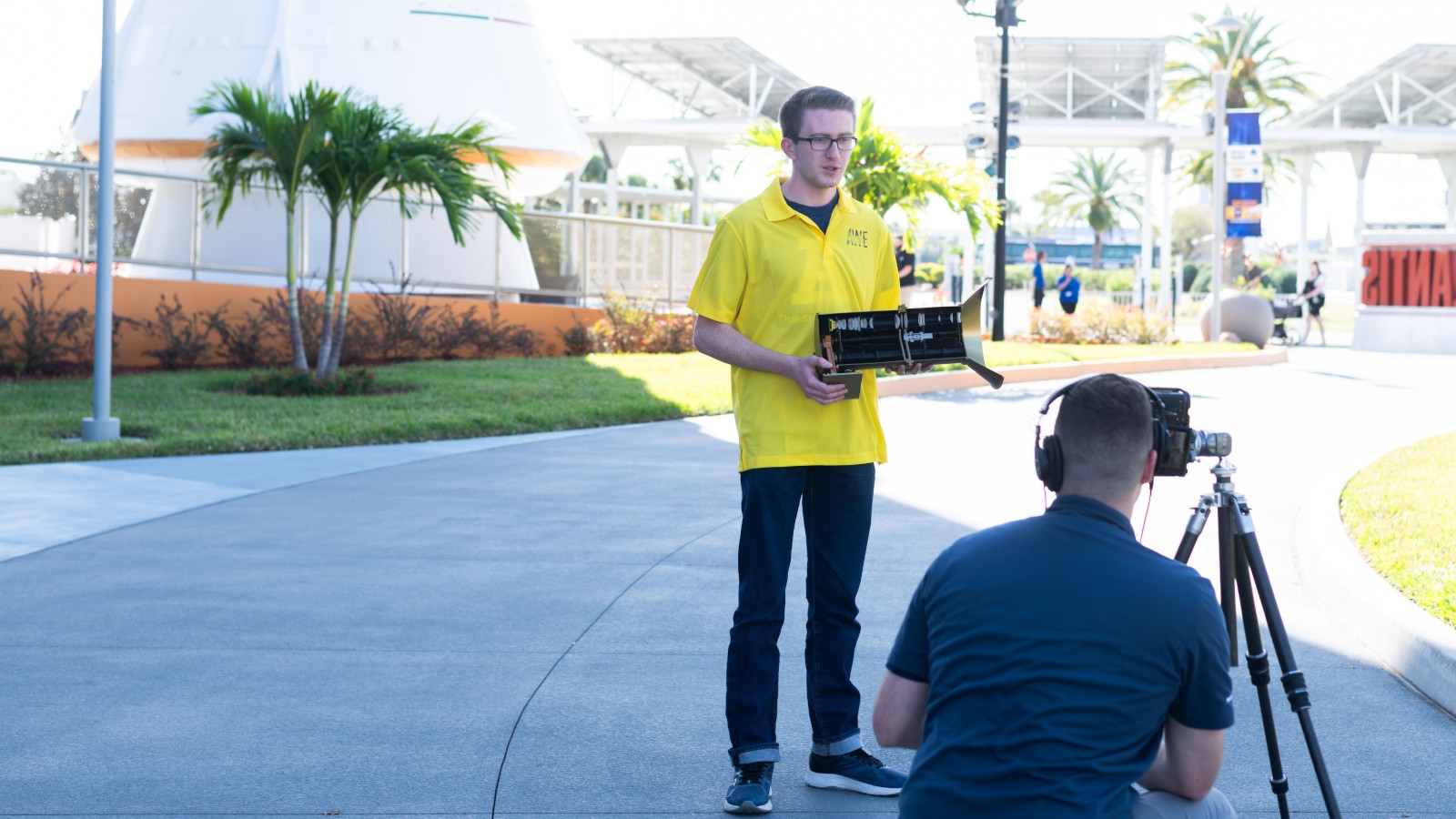 Scientist holding instrument is interviewed on camera.