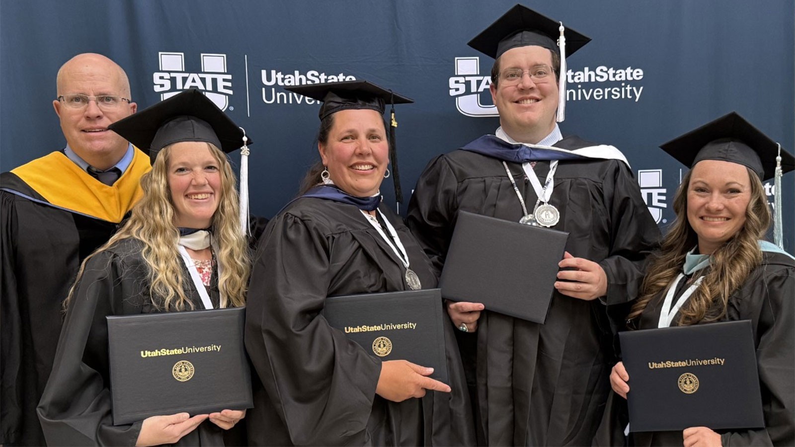 People in graduation robes posing with certificates.