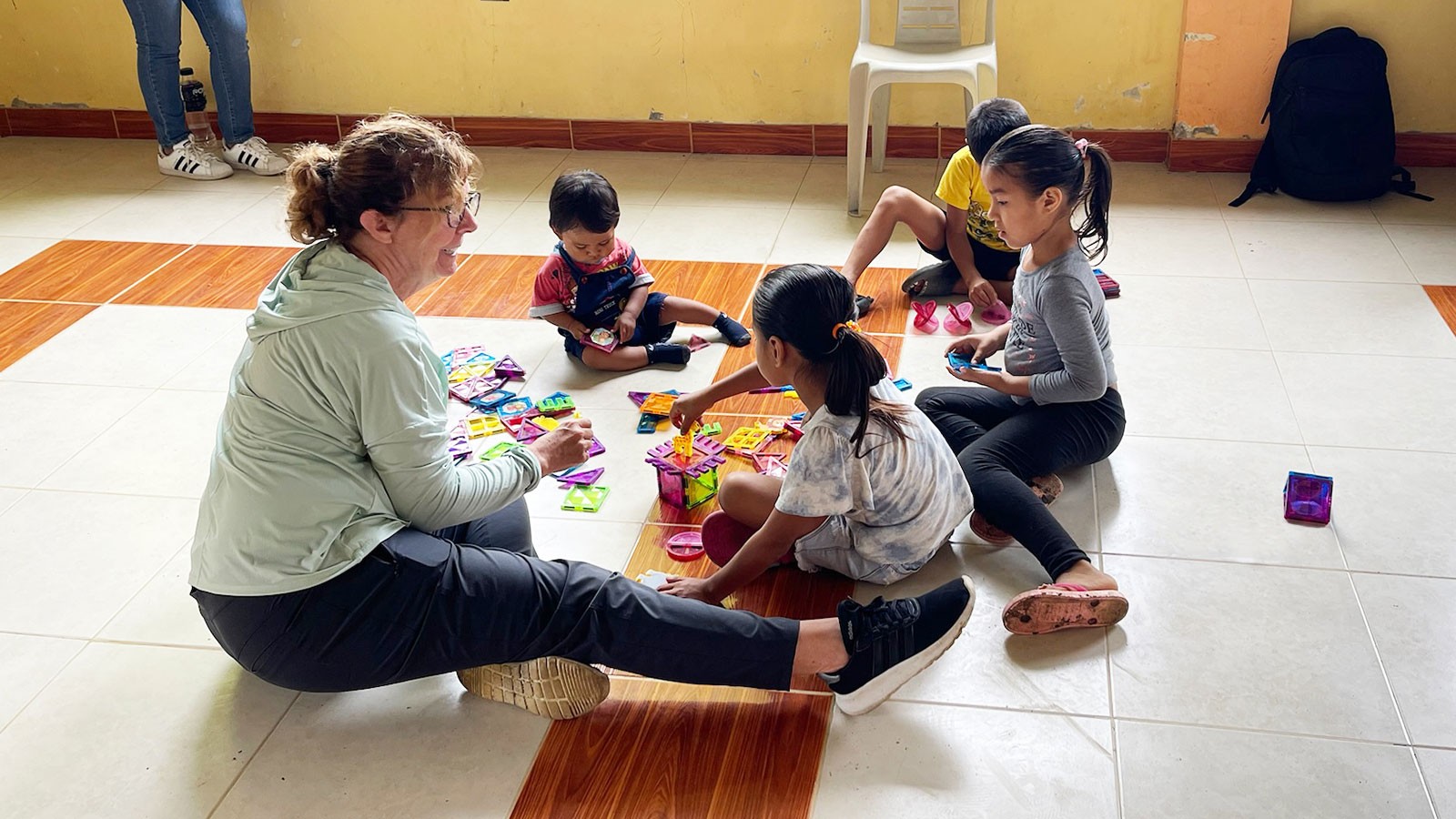 A teacher working with young children in a schoolroom.