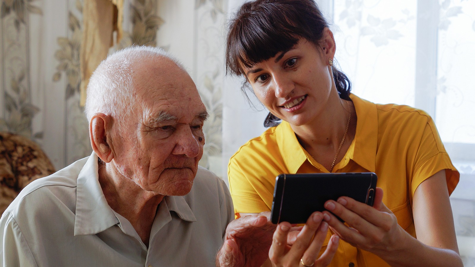 A caregiver watching a video with an older adult.