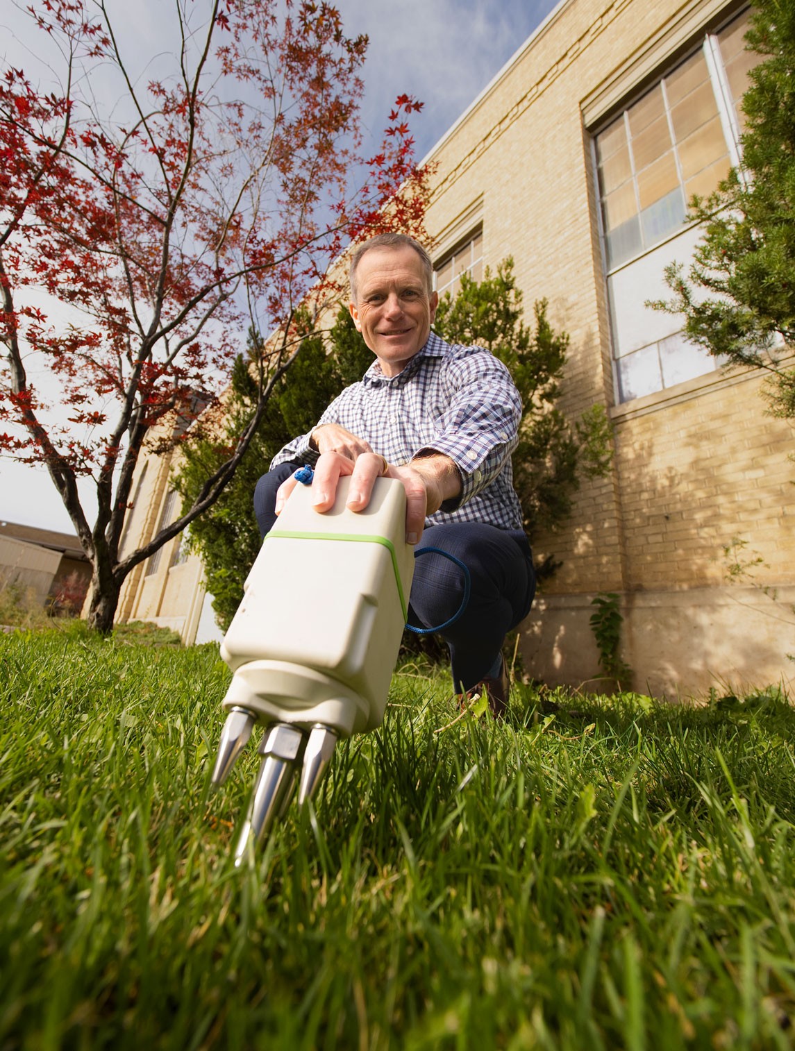 Brady Cox using a scientific instrument outside a USU building.