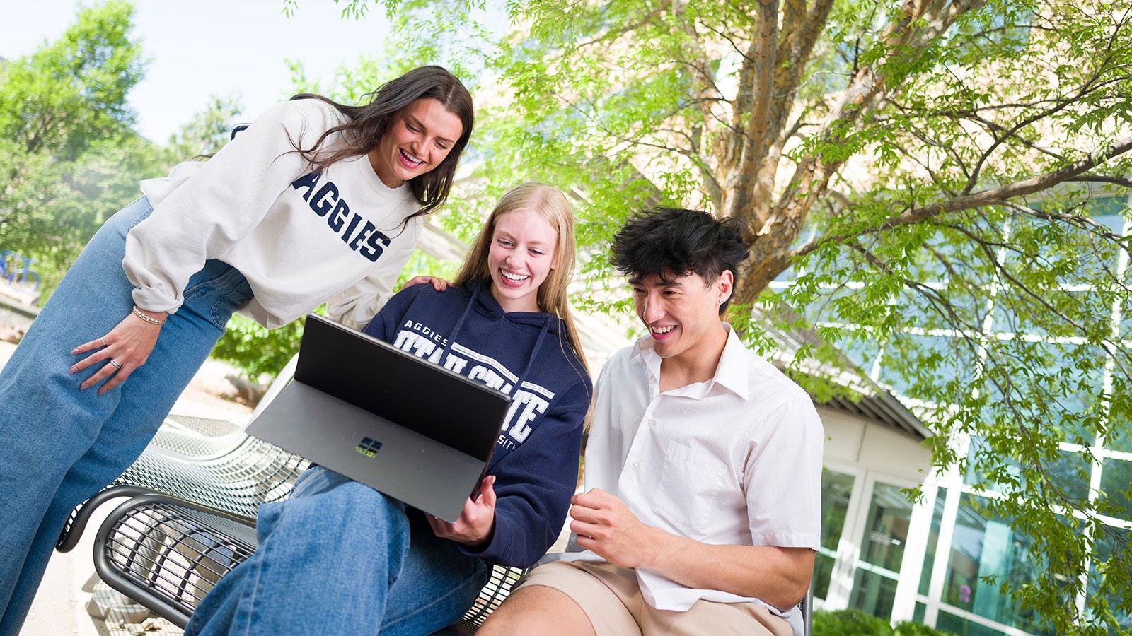 Students outside looking at a laptop.
