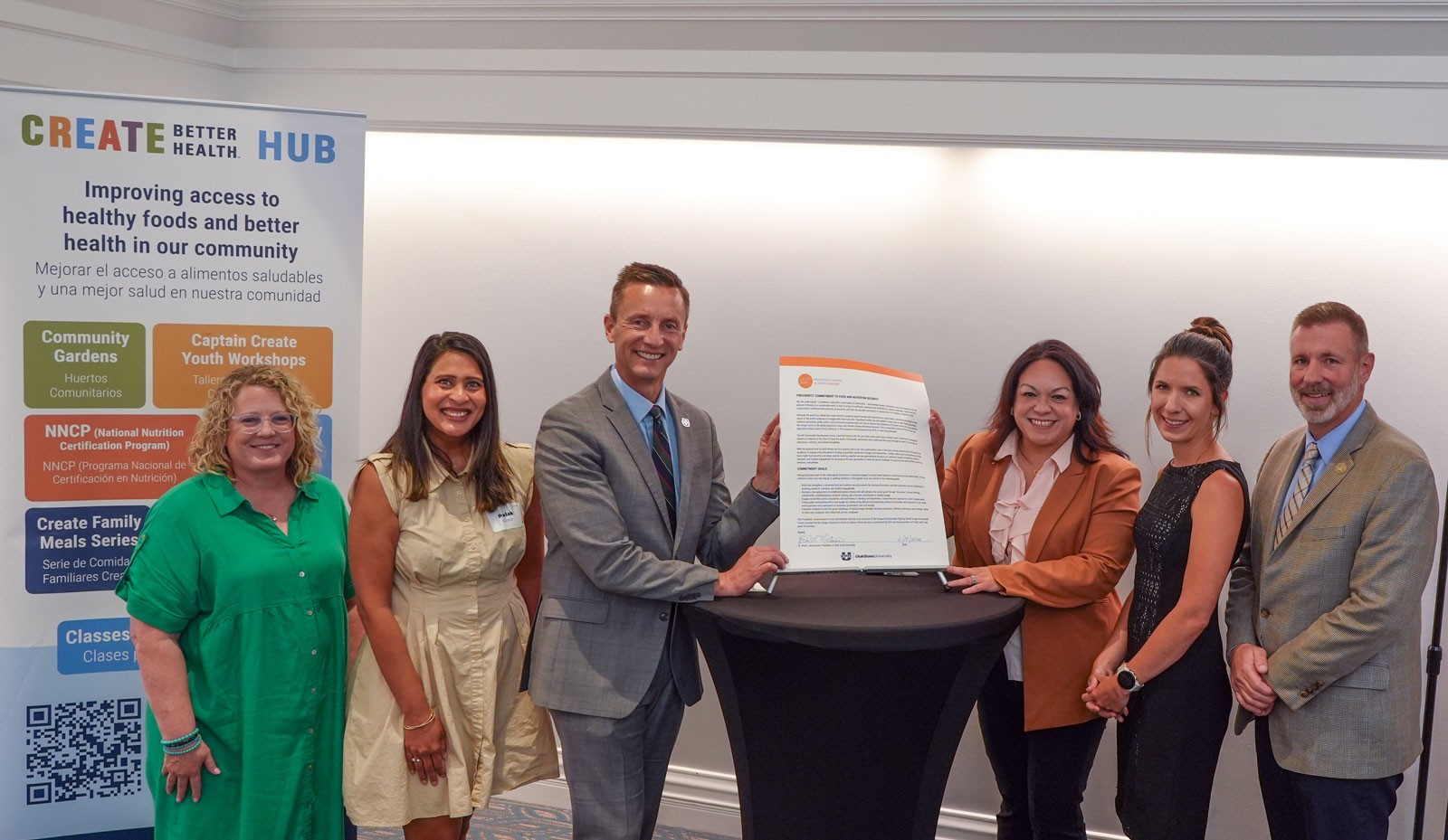 People posing with a document at an event.