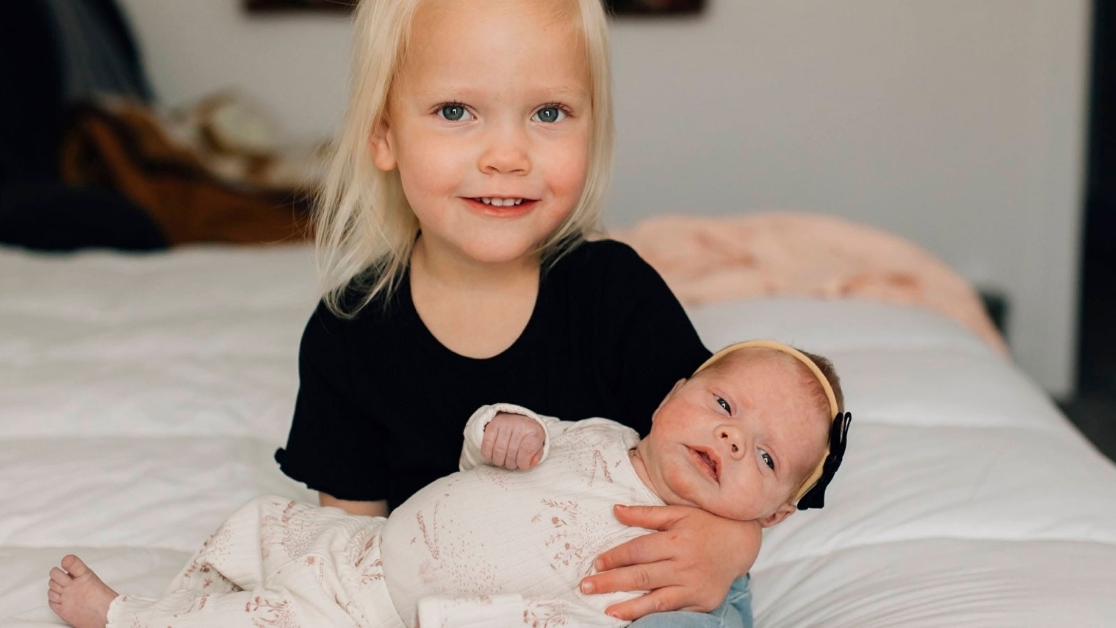 A toddler holding a newborn.