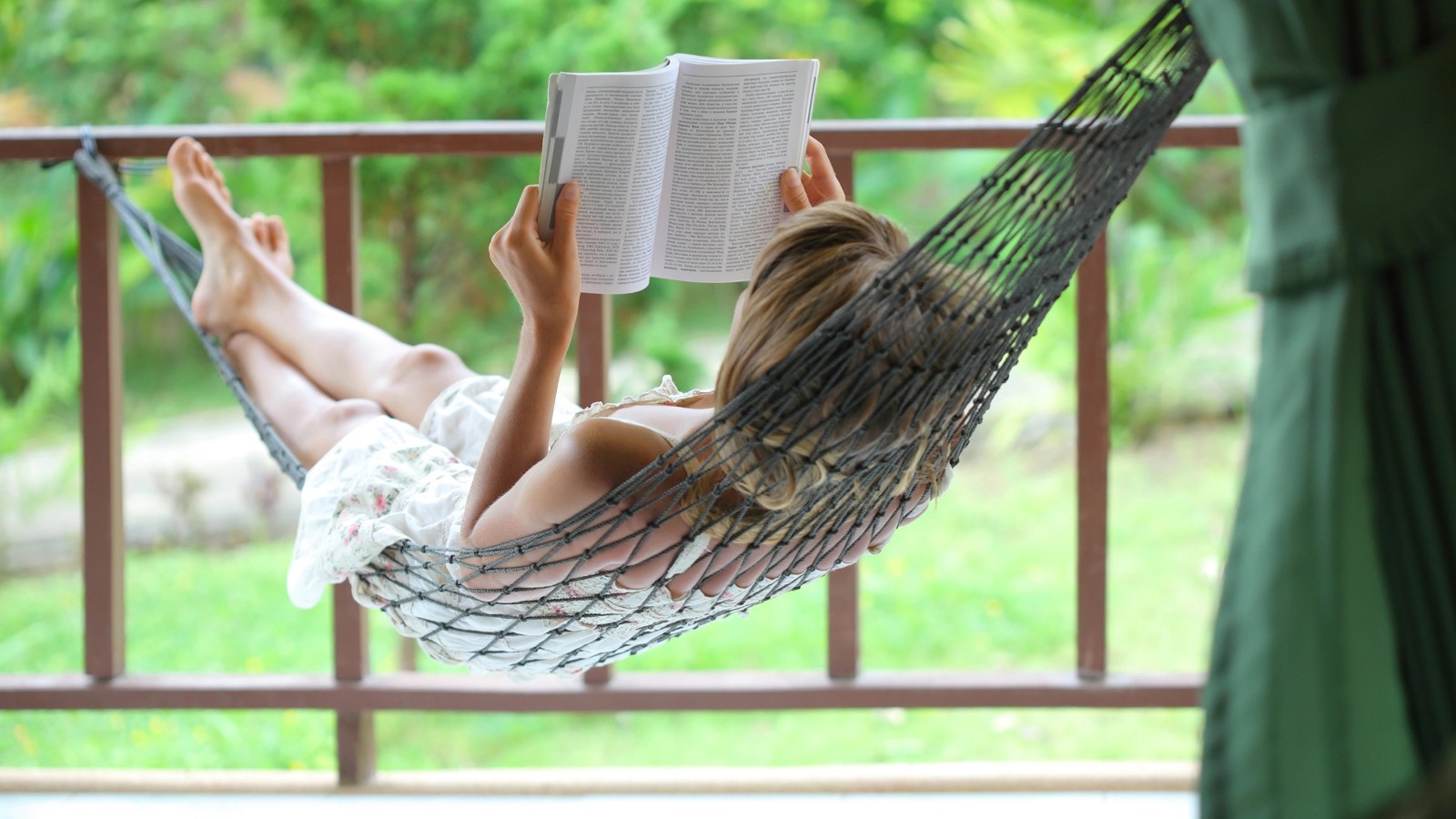 A person reading in a hammock.