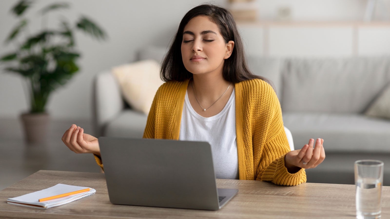 A person meditating by a laptop.