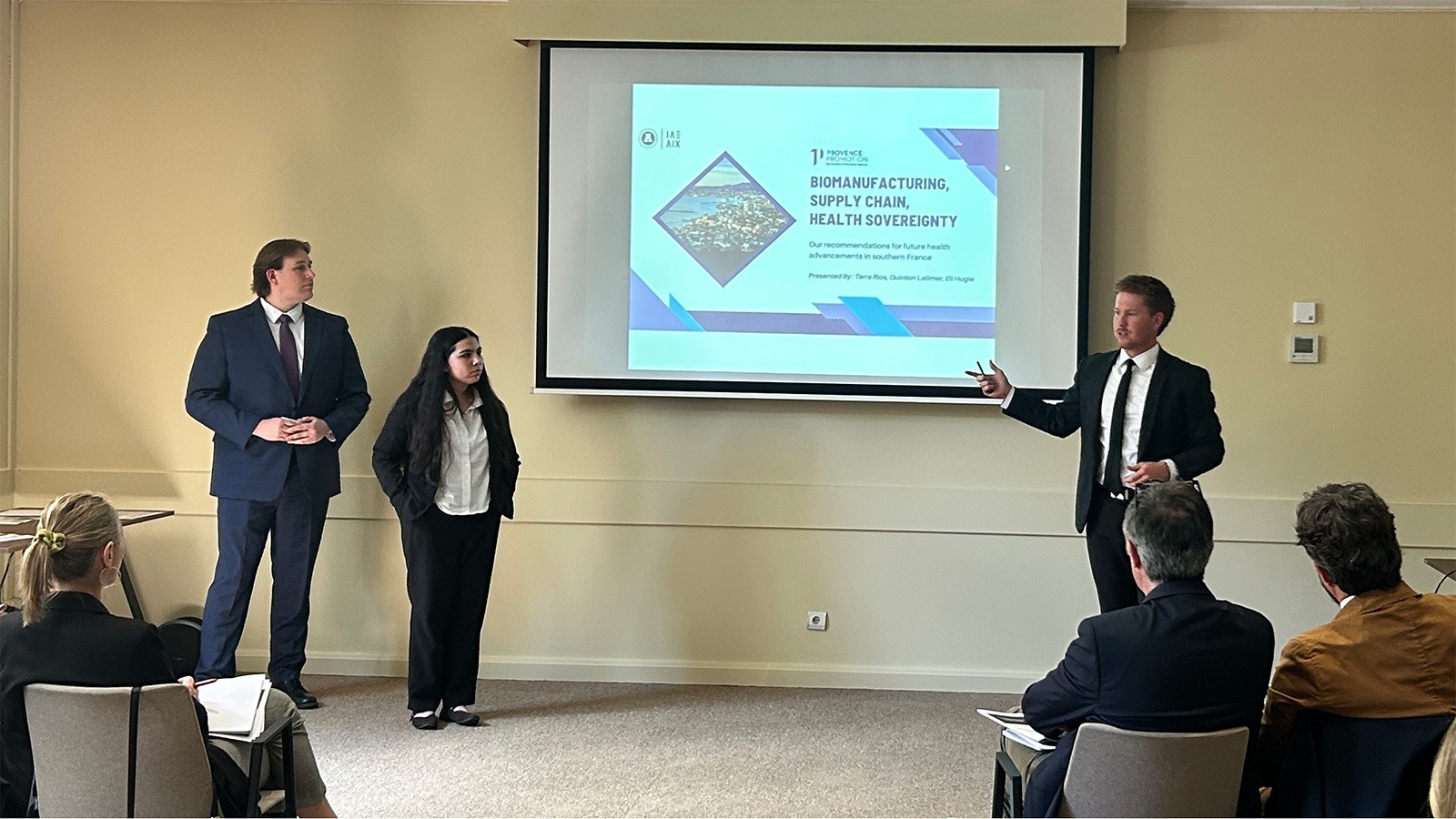 A group of students stand in front of a conference room giving a presentation