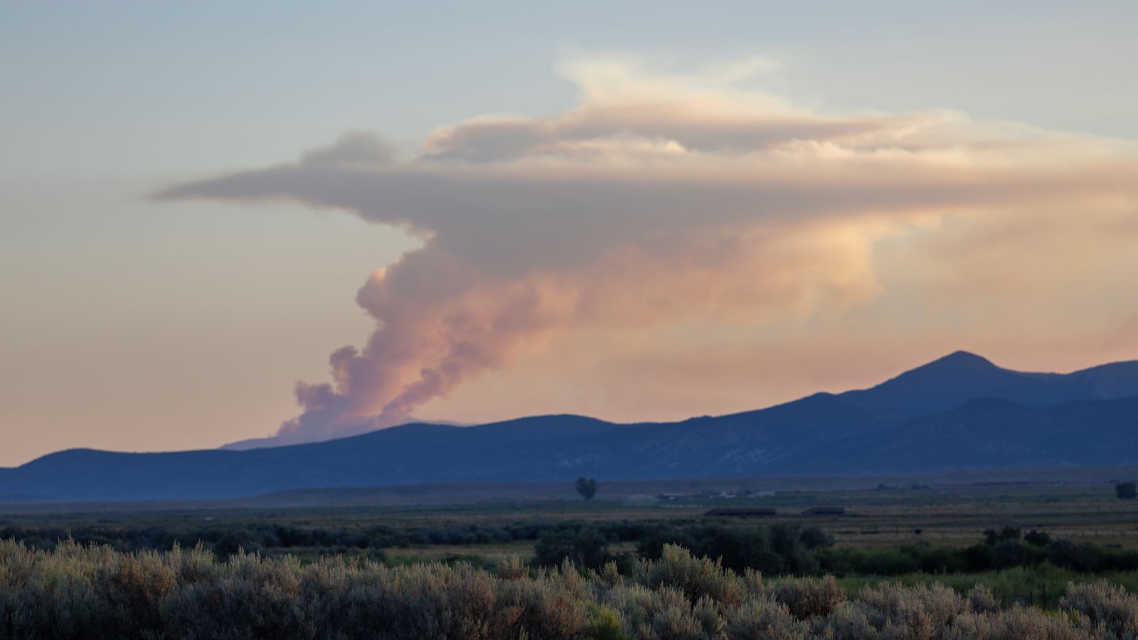 Smoke rising from a wildfire on a mountainside.