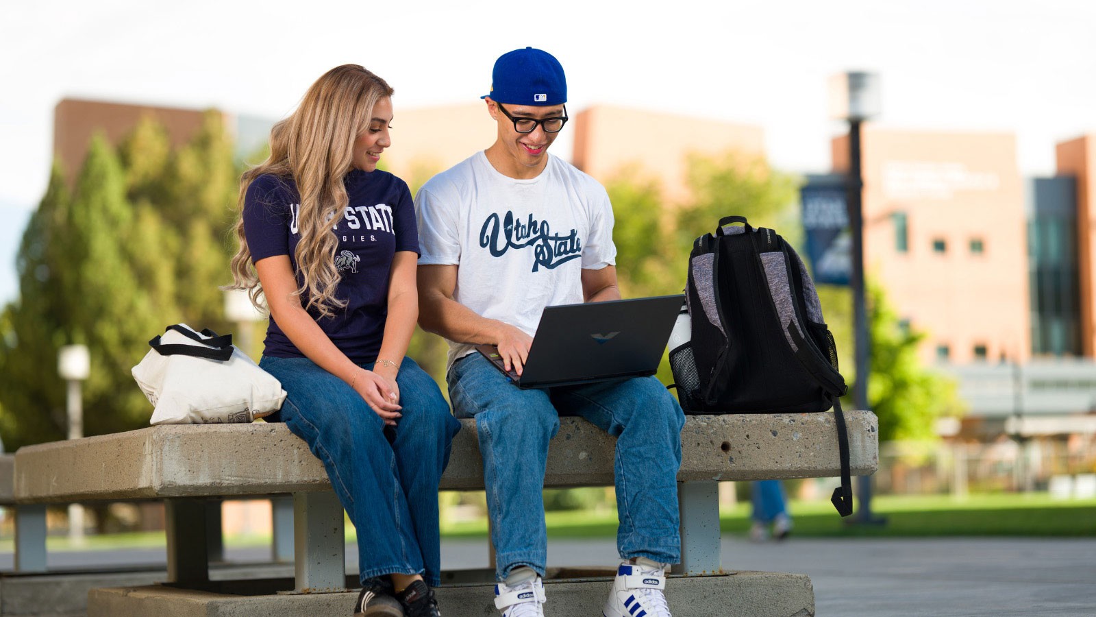 People wearing Utah State apparel and using a laptop.