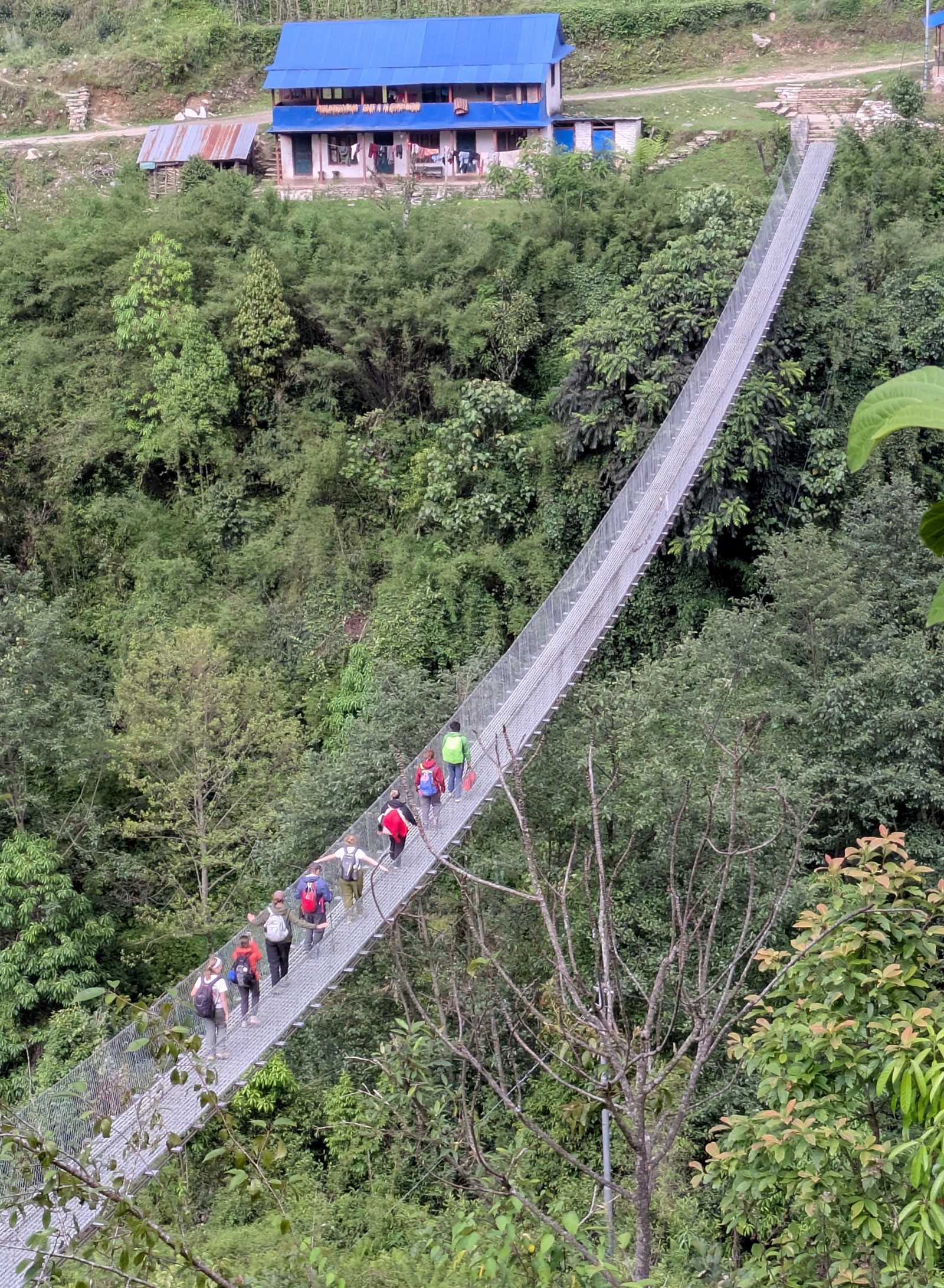 People crossing a foot bridge while hiking in Nepal.