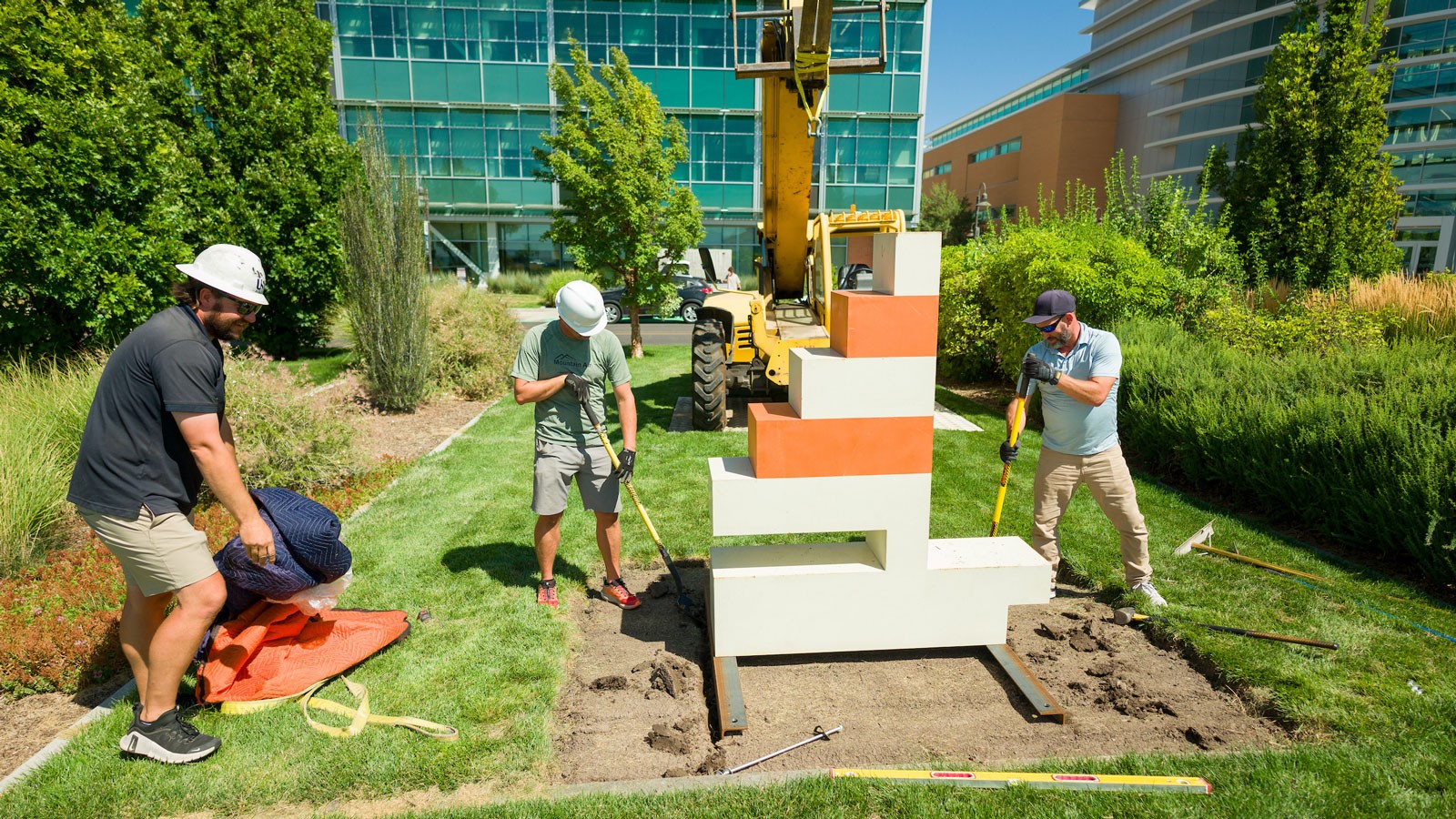Workers installing a sculpture of a pixelated sailboat.