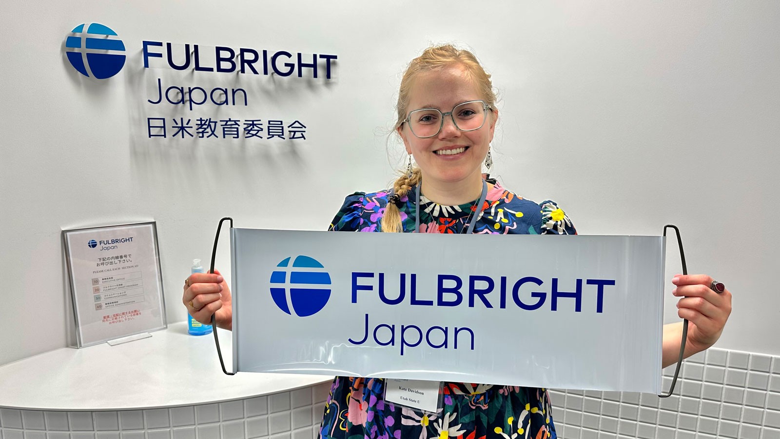Katie Davidson holding a banner that says "Fulbright Japan."