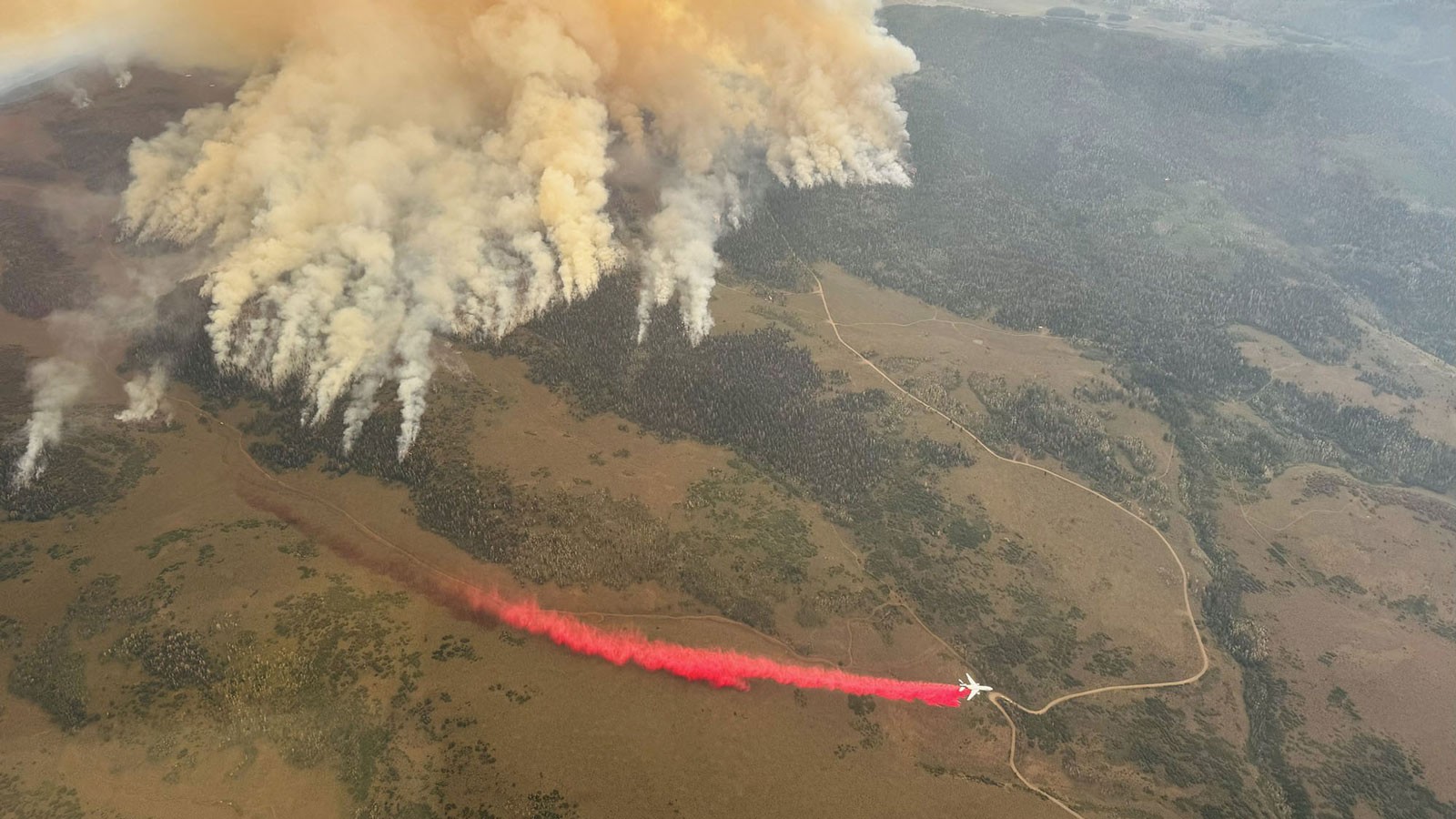 A plane dropping fire retardant near a wildfire.