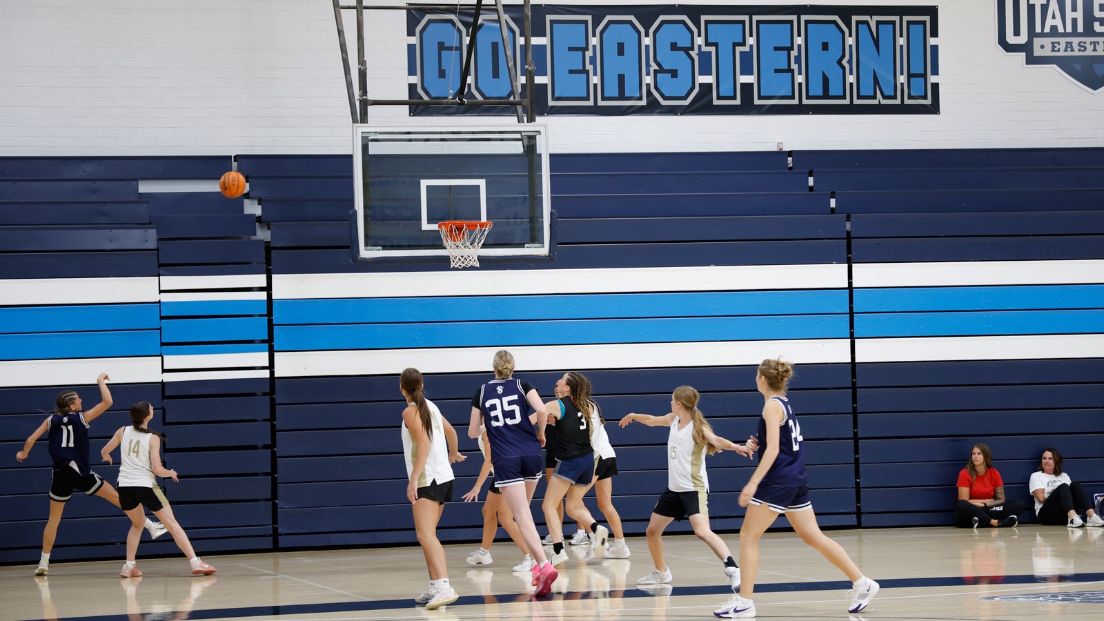 People playing basketball. Sign reads: Go Eastern!