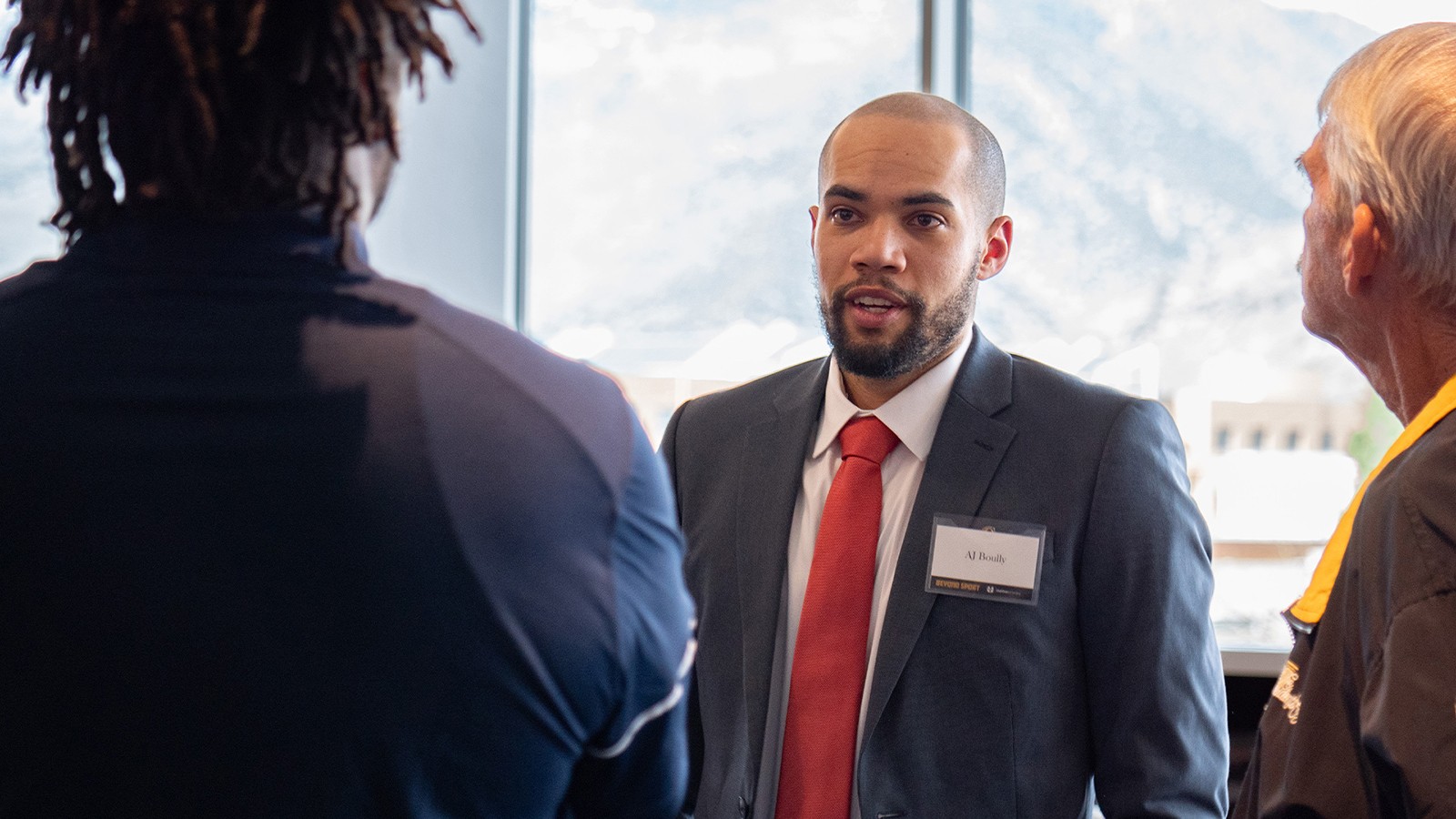 A man in a suit speaks in a crowd.