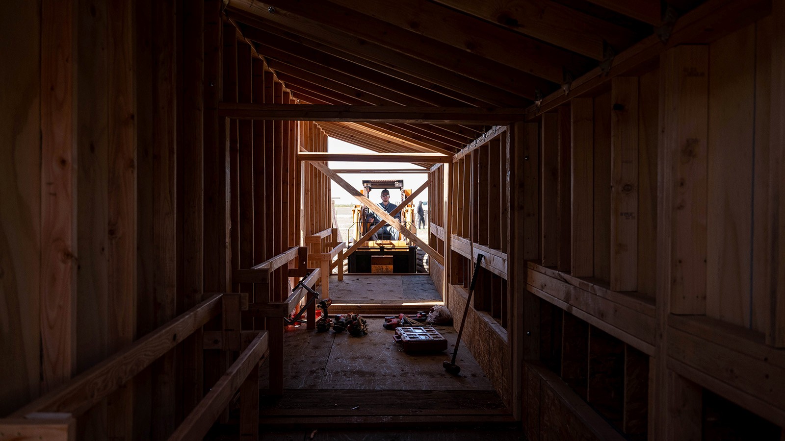 A man operates a skid steer to connect the coop sections together