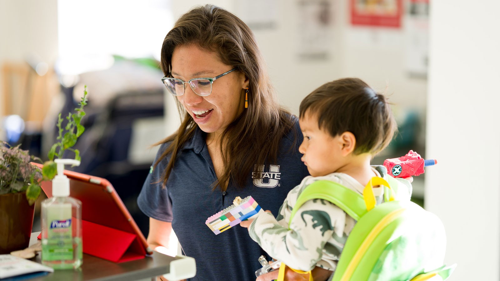 A person in a Utah State uniform holding a child.