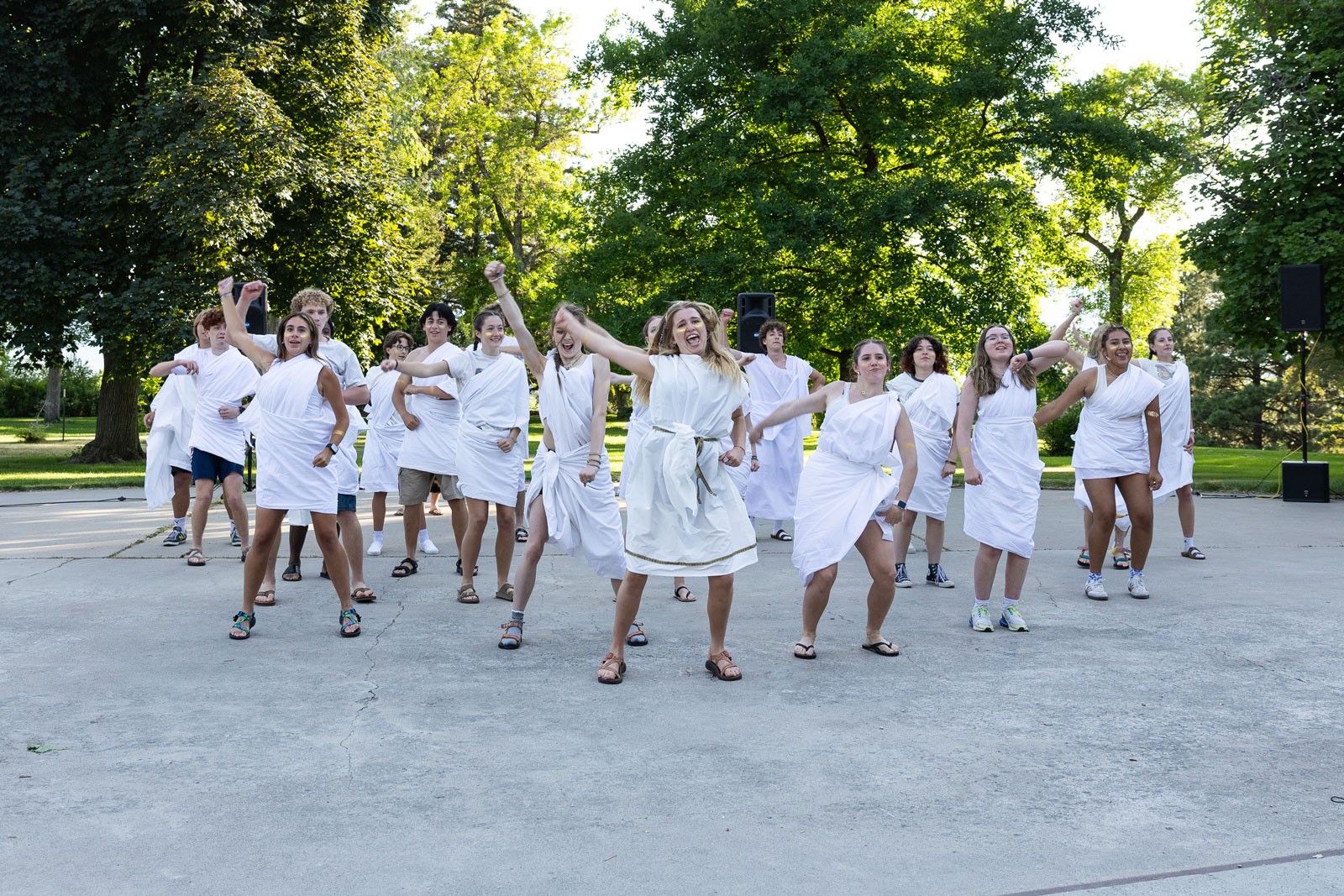 Students wearing togas perform a dance outdoors.