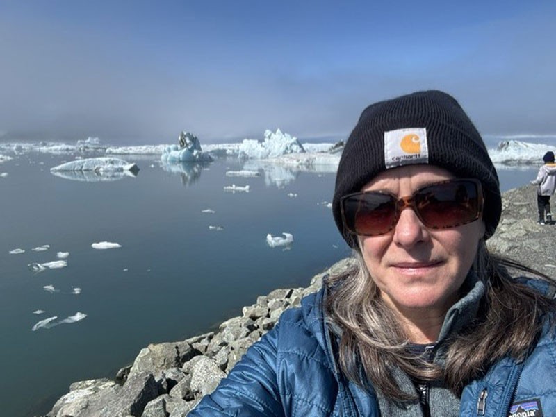 Karen Beard on a rocky, icy beach.