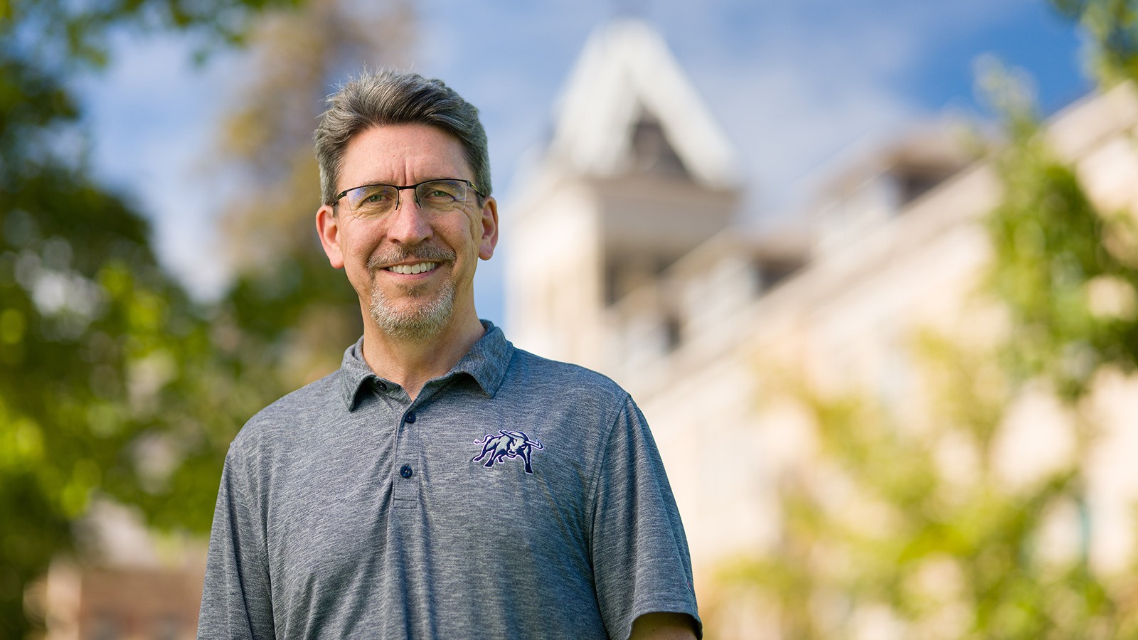 Interim President Al Smith wears a grey USU polo in front of Old Main