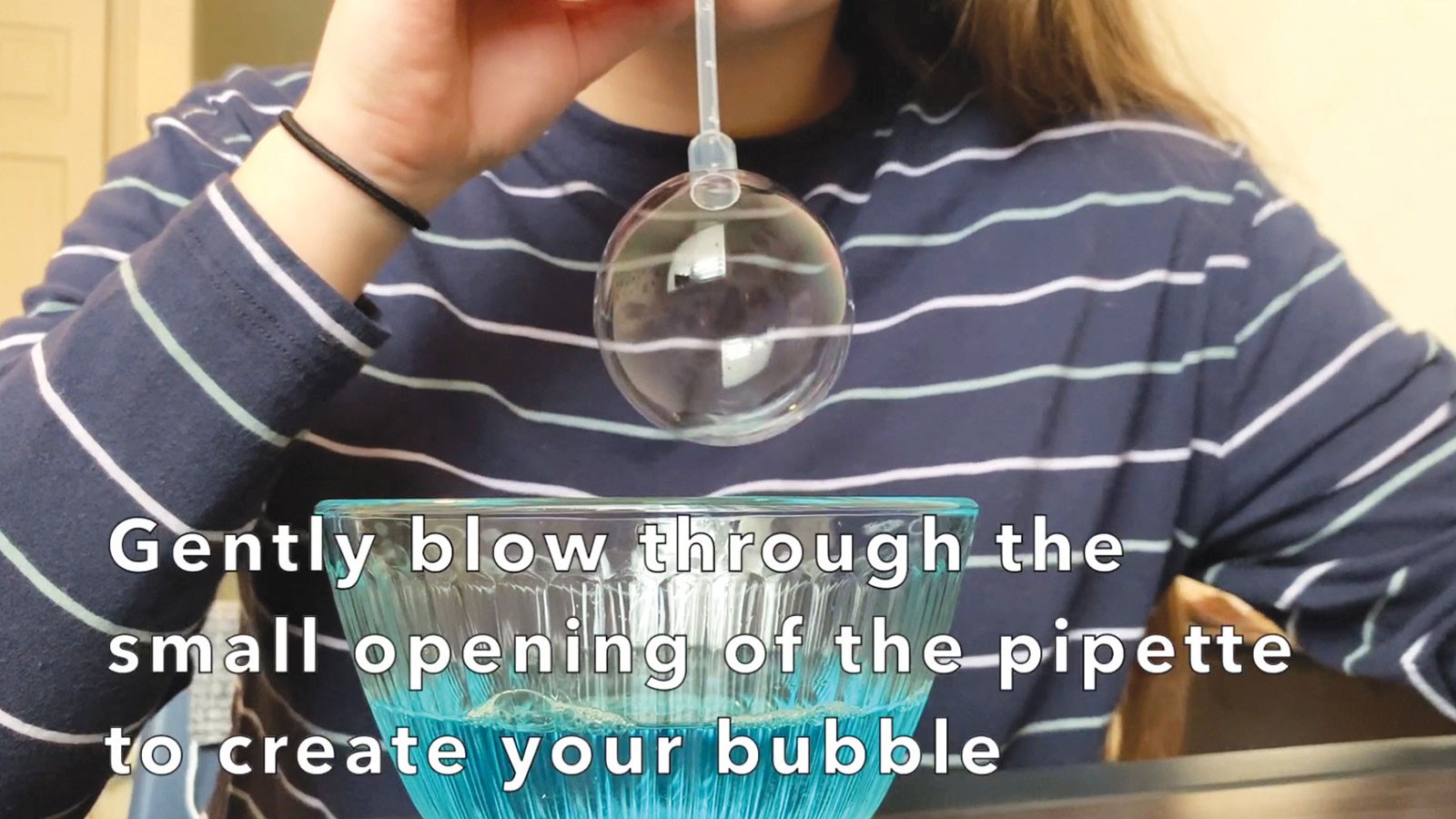 A learning video shows instructions for blowing a bubble as part of a science experiment.