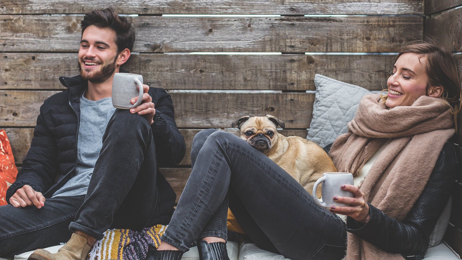 A couple relaxing on an outside deck with their dog.