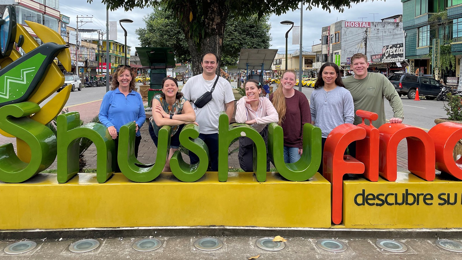 A group of people pose for a photo behind a sign.