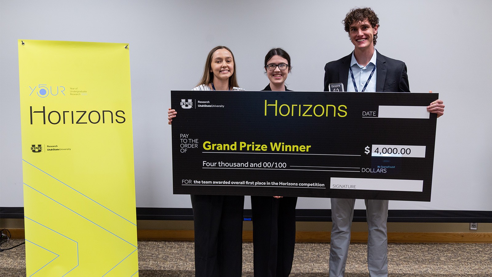 Students hold a check after winning the $4,000 grand prize