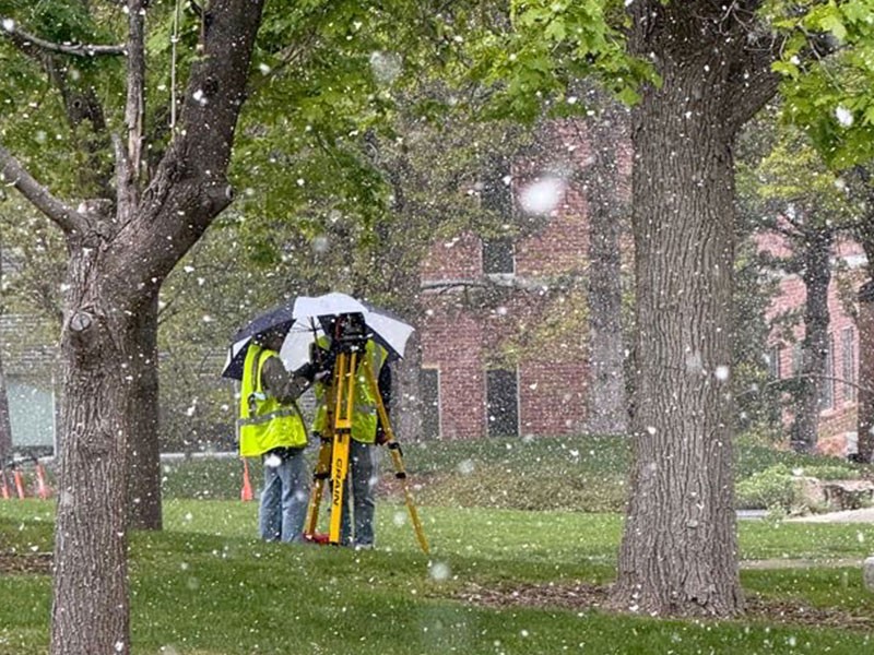 People using construction surveying equipment as snow falls.