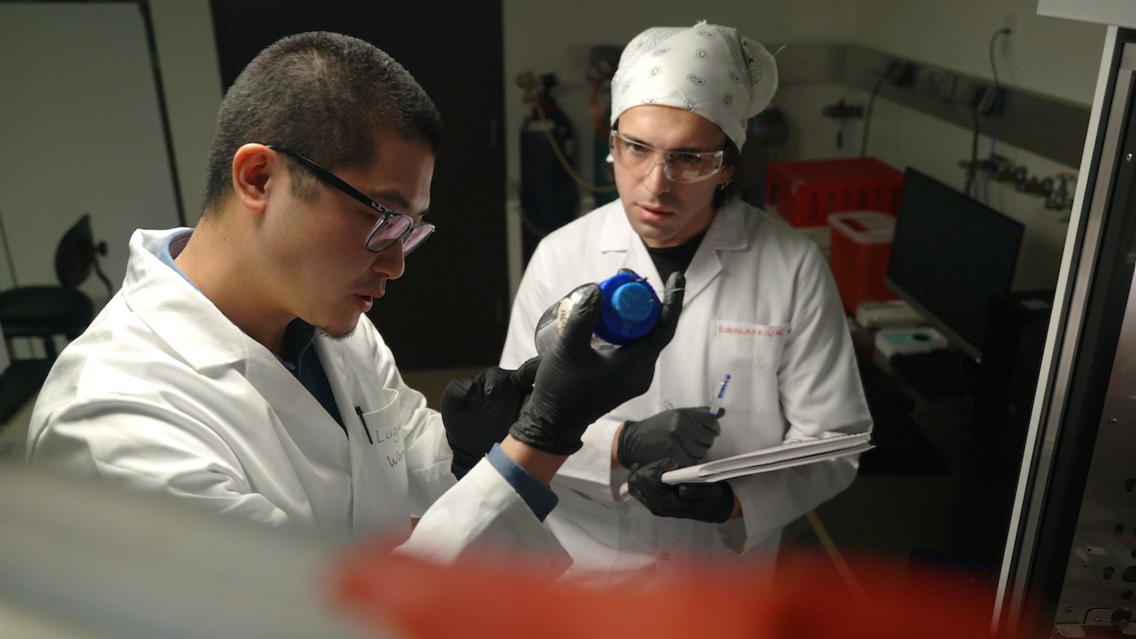 Two scientists inspecting a container.