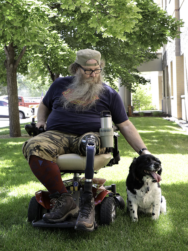 a man in a wheelchair pets a dog