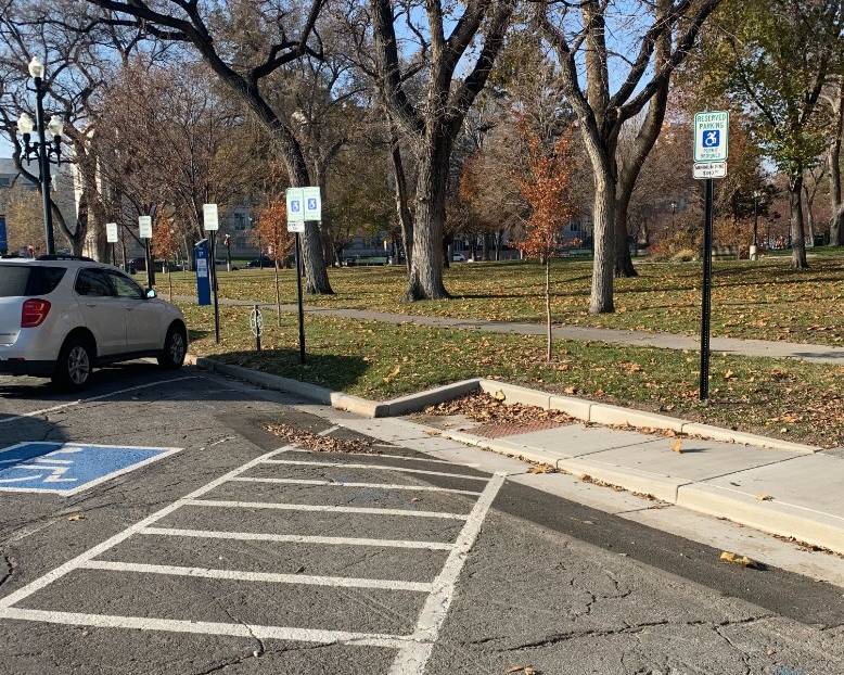 Permanent ramp next to accessible parking facing a park.
