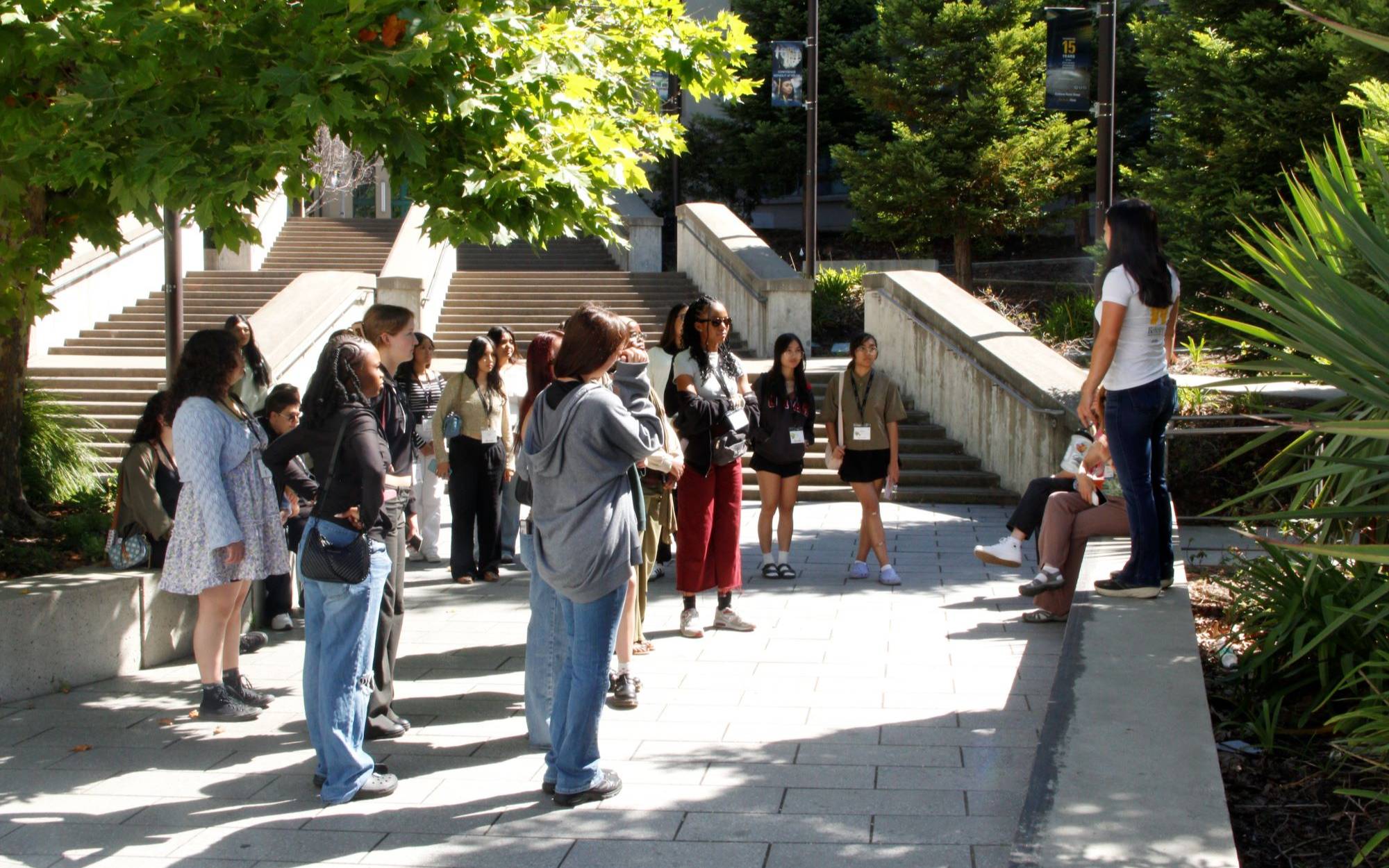 college tour guide standing on short cement platform and talking to group of students