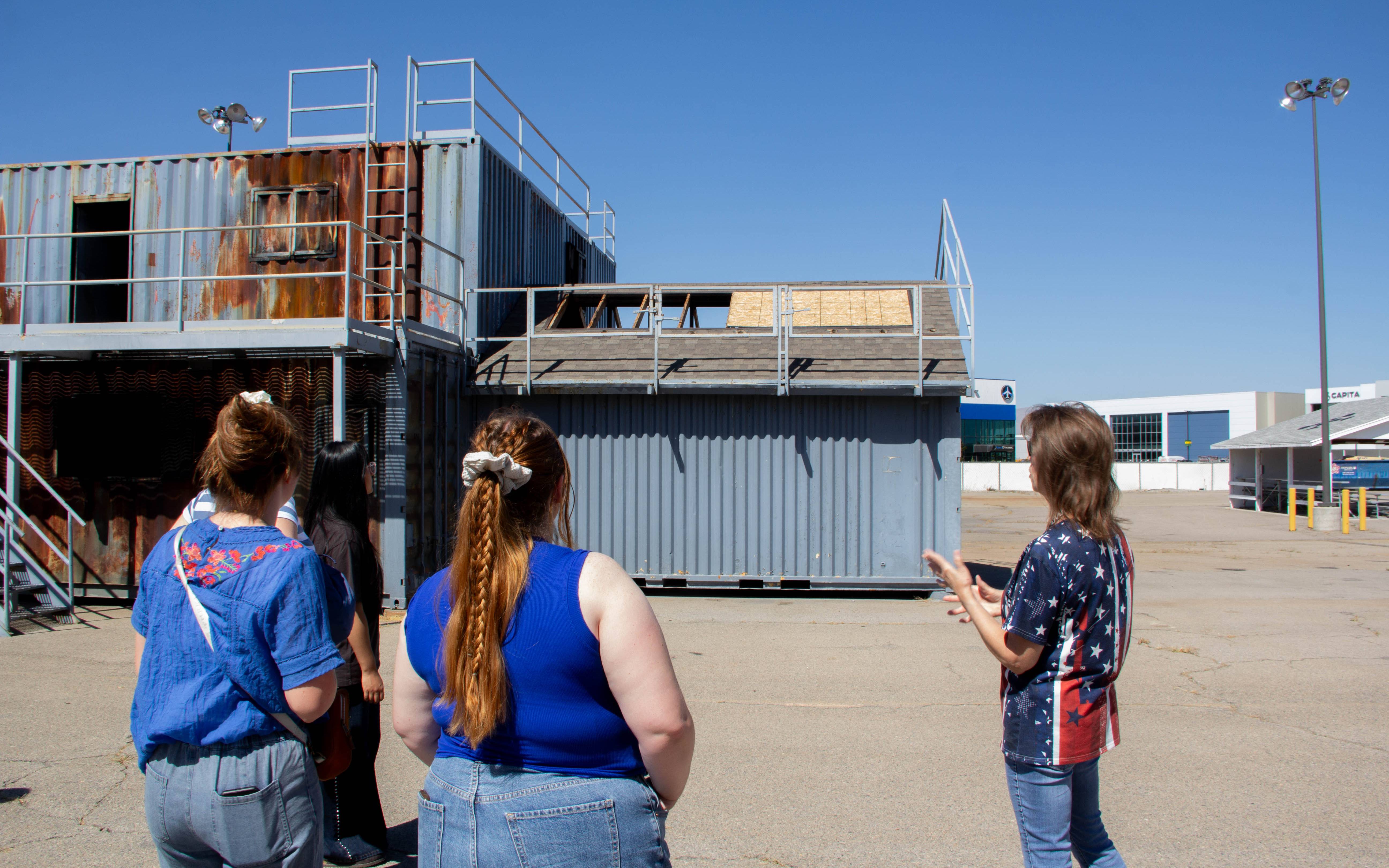 students and a guide standing outside, looking at several large metal containers as part of a training course