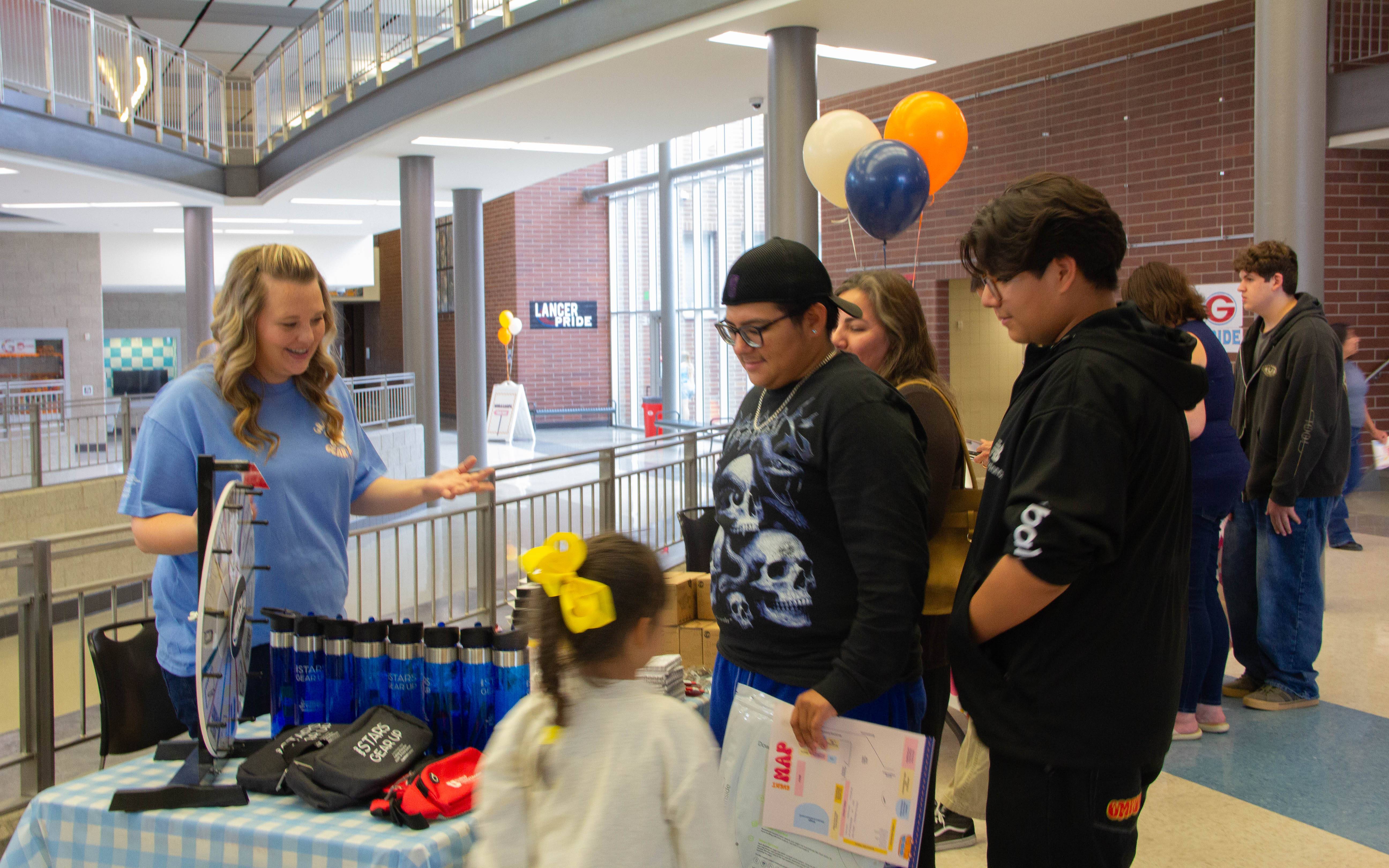 students and advisor gathered around a table, with USU STARS GEAR UP prizes and balloons