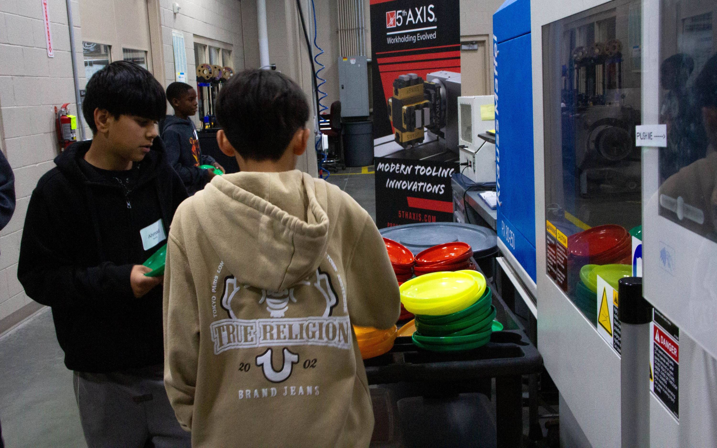 two students examining technical equipment in a hallway