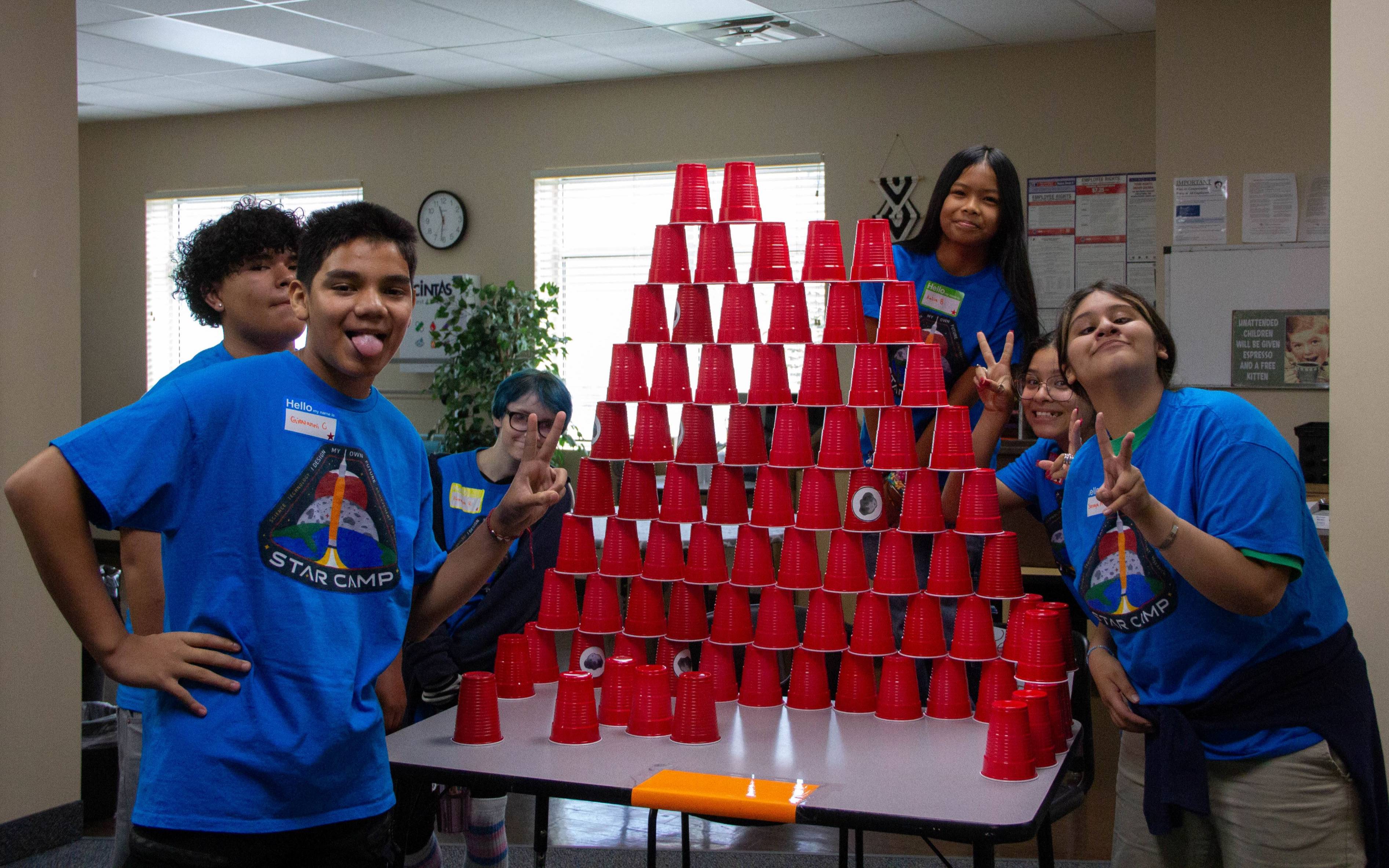 students posing in front of a large tower made of plastic cups